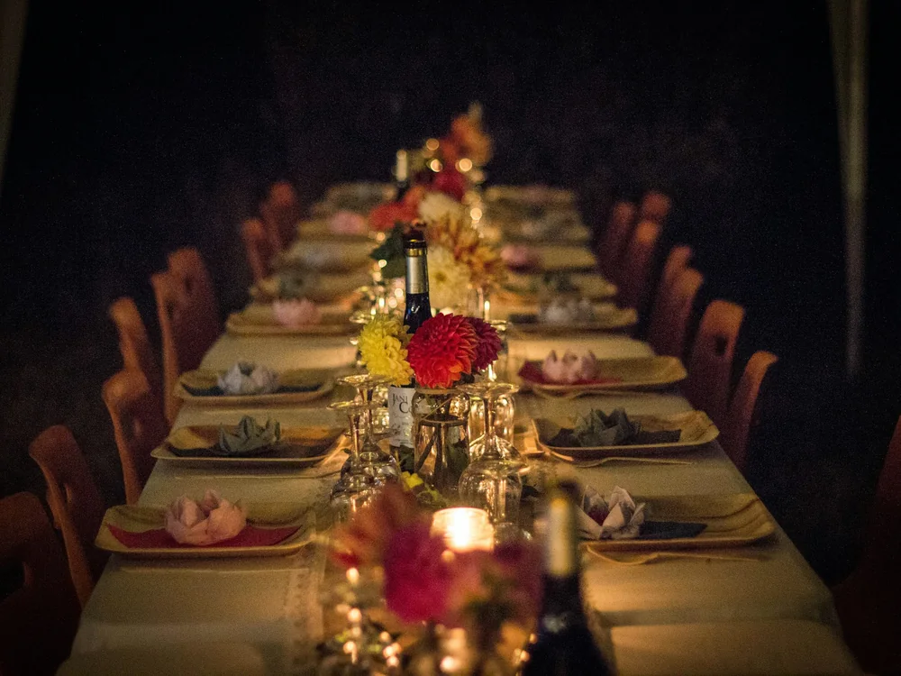 A long dinner table set with flowers and candles, ready for guests